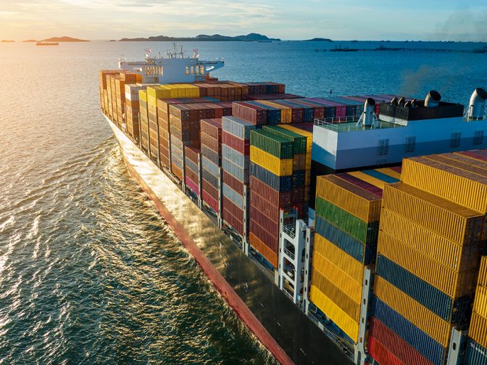 Aerial side view of cargo ship carrying container and running for export  goods  from  cargo yard port to custom ocean concept technology transportation , customs clearance.